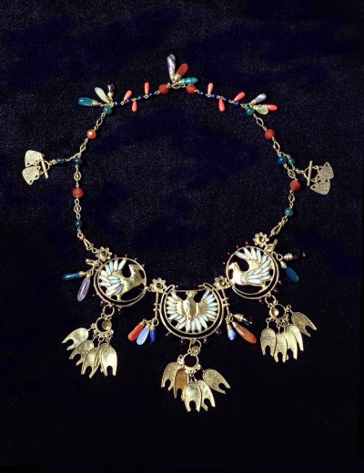 An ornate gold necklace with three circular motifs with doves and semi-precious coloured beads and droplets throughout the chain