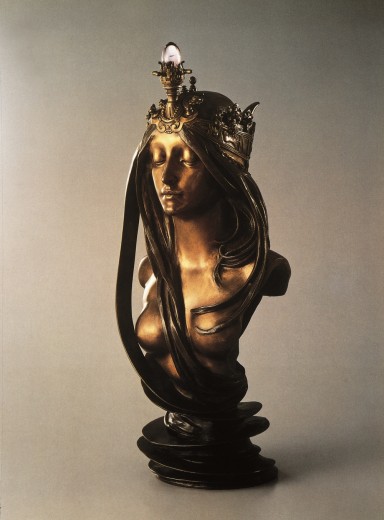 The bust of a woman with bare breasts, long and ondulating hair and a crown capped with a light fitting