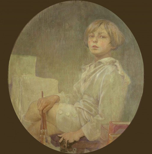 Young boy in a white shirt and shorts sitting cross-legged with a paintbrush in his right hand in front of a blank canvas