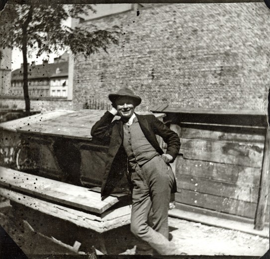 A smiling Mašek leaning against a wooden structure in the street
