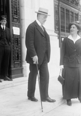Charles Richard Crane A man in a suit with a hat and a cane walks down steps in front of a building with a cast iron entrance with a young man standing in the doorway and a woman standing on the steps