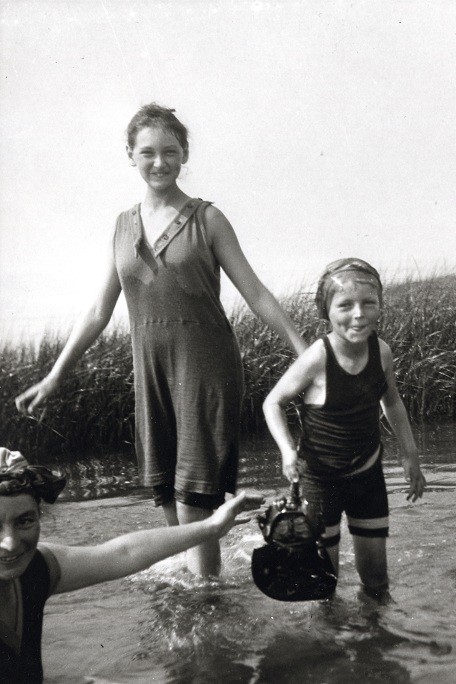 Maruška reclining in shallow water next to Jiří and Jaroslava with rushes behind