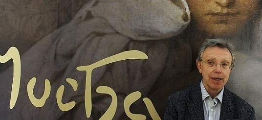 John Mucha, President of the Mucha Foundation John Mucha standing in front of a Mucha exhibition poster