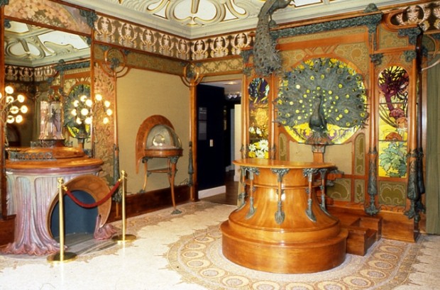 A general view of the reconstructed interior with a peacock decoration on the far wall, a wooden circular counter and a presentation case and ornate fireplace on the left wall