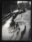 A procession of men through a Paris street (seen from above) with deep shadows cast from top right to bottom left